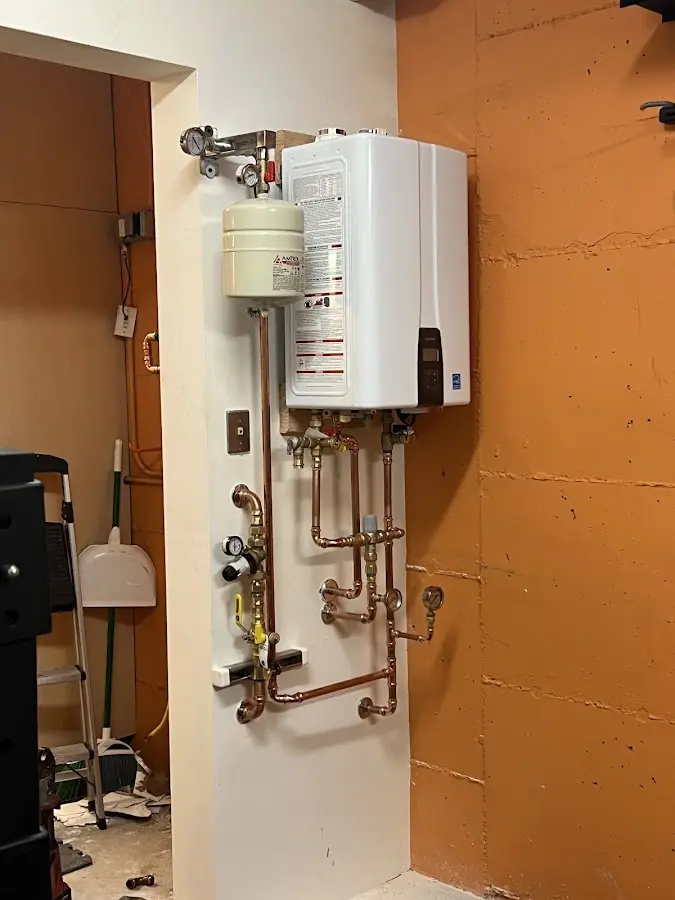 Plumbing technician inspecting water heater connections in Madras
